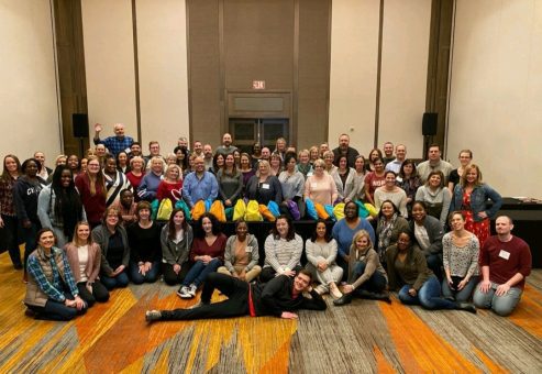 Large group gathered together for the Team Disaster Relief event, proudly holding their colorful bags. They collaborated to assemble disaster relief kits, engaging in teamwork and problem-solving challenges to support recovery efforts.