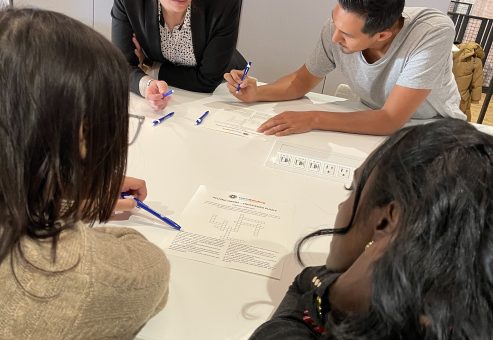 Team members collaborating and problem-solving during the Team Disaster Relief event, working together to plan and assemble disaster relief care kits. The activity emphasizes teamwork and communication skills.