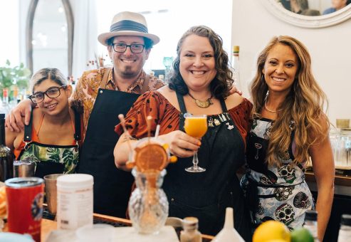 Team members proudly posing with their cocktail creations during a mixology class. The fun, interactive event encourages creativity and teamwork while learning the art of cocktail crafting.
