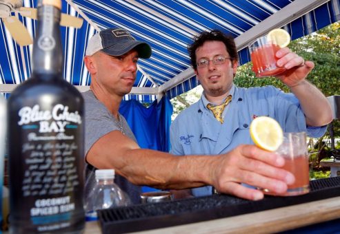 Two team members toasting with freshly made cocktails at a mixology event. The hands-on class promotes teamwork and creativity as participants craft and enjoy their own drinks together.